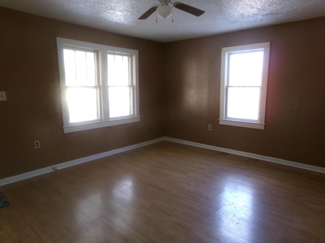 unfurnished room with ceiling fan, a textured ceiling, baseboards, and wood finished floors