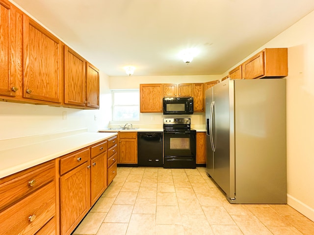 kitchen featuring light tile patterned floors, black appliances, and sink