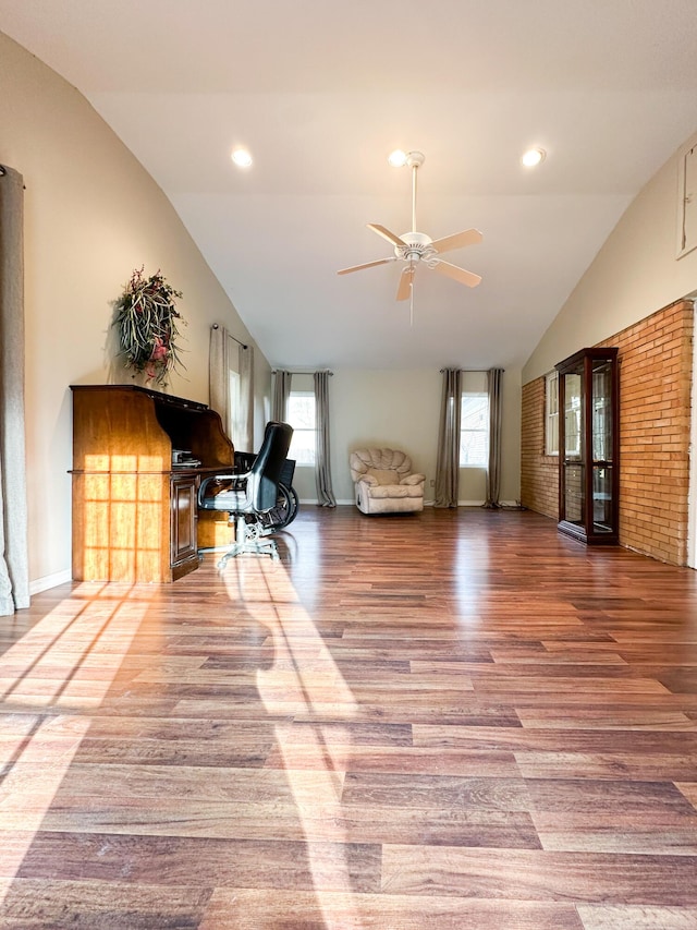 interior space with hardwood / wood-style flooring, vaulted ceiling, brick wall, and ceiling fan