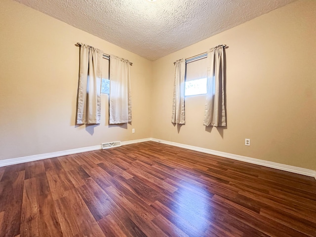 unfurnished room with dark hardwood / wood-style floors and a textured ceiling