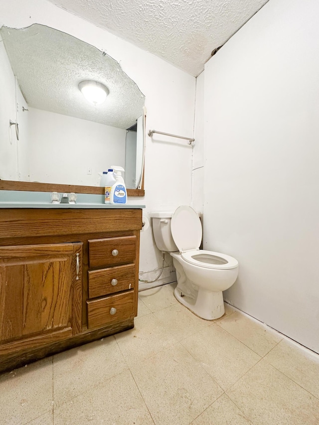 bathroom with vanity, toilet, and a textured ceiling