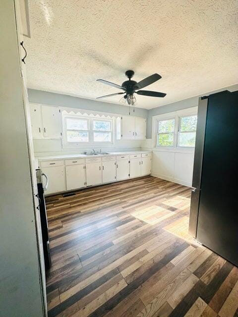 kitchen with white cabinets, ceiling fan, hardwood / wood-style floors, and a textured ceiling