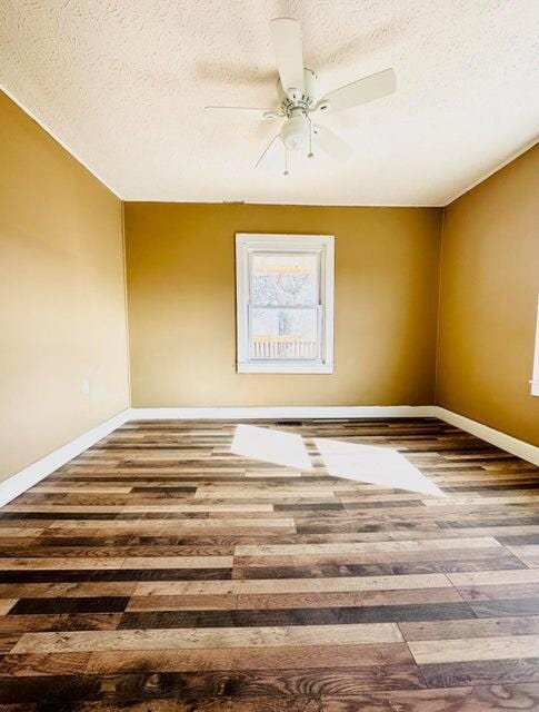 empty room featuring ceiling fan, wood-type flooring, and a textured ceiling