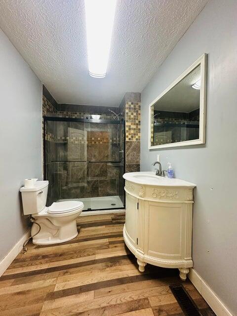 bathroom with toilet, hardwood / wood-style floors, a textured ceiling, and walk in shower