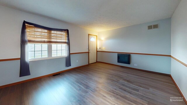 unfurnished living room with a textured ceiling, carpet floors, a wood stove, and lofted ceiling