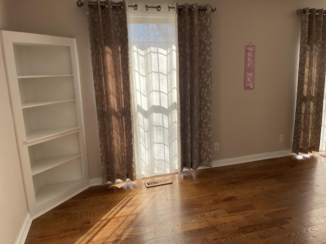 unfurnished room featuring built in features and dark wood-type flooring