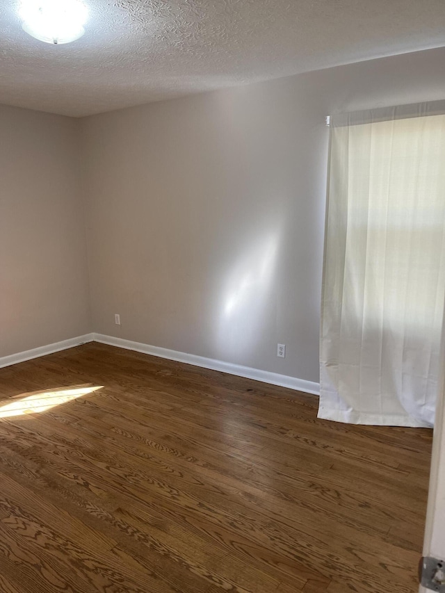 unfurnished room with dark hardwood / wood-style flooring and a textured ceiling