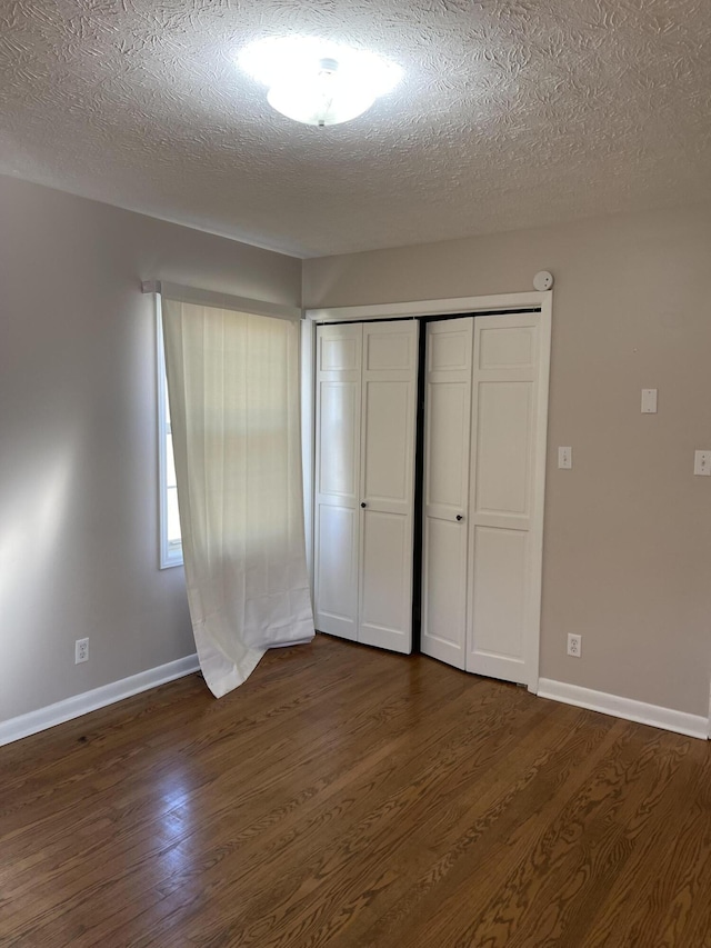 unfurnished bedroom featuring dark hardwood / wood-style floors, a textured ceiling, and a closet