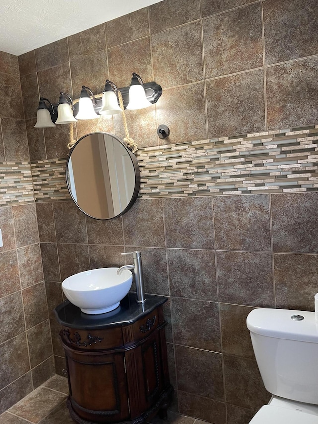 half bath with toilet, vanity, and tile walls