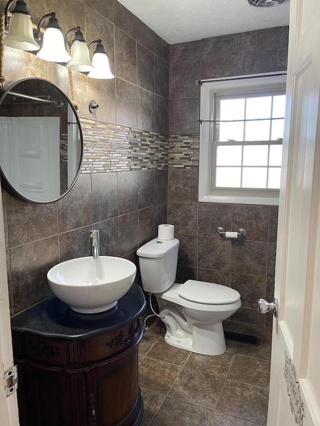 bathroom with vanity, toilet, and tile walls