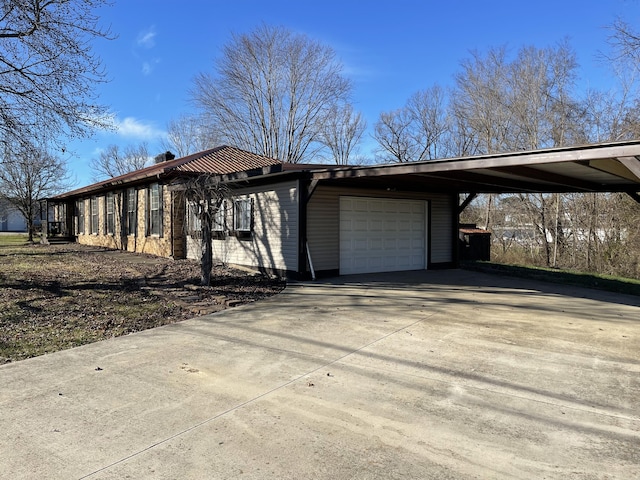 view of front of house featuring concrete driveway, an attached carport, a chimney, and an attached garage