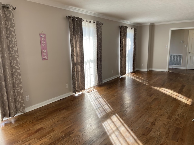 spare room featuring dark wood-type flooring, visible vents, and crown molding