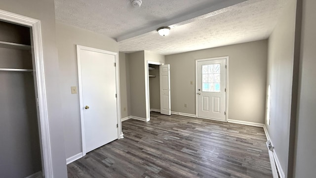 unfurnished bedroom featuring a textured ceiling, multiple closets, and dark hardwood / wood-style floors