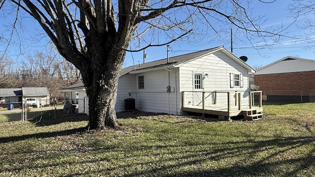 rear view of property featuring a lawn, a wooden deck, and central air condition unit