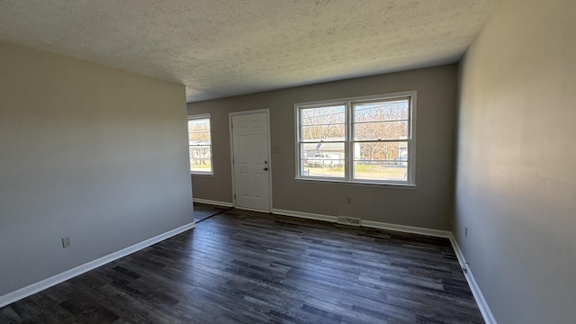 interior space with a textured ceiling, dark hardwood / wood-style floors, and a wealth of natural light