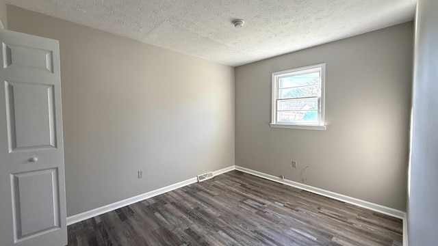 spare room with dark hardwood / wood-style flooring and a textured ceiling