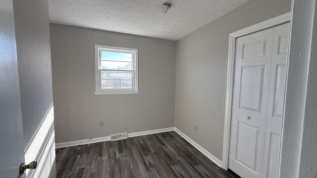 empty room with a textured ceiling and dark wood-type flooring