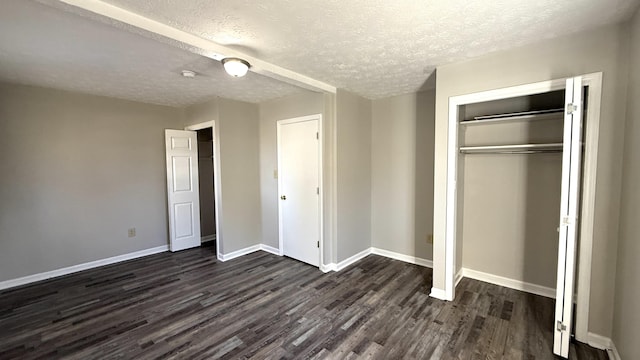 unfurnished bedroom with a textured ceiling, dark hardwood / wood-style flooring, and a closet