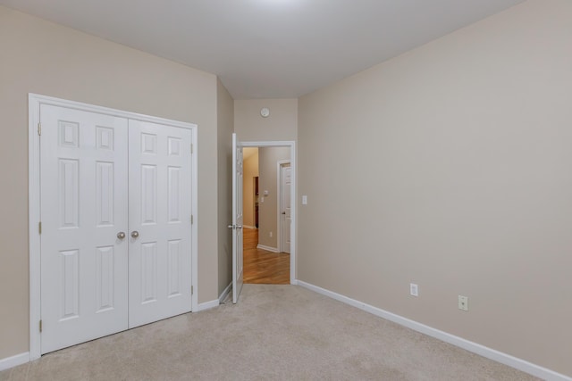 unfurnished bedroom featuring light colored carpet and a closet