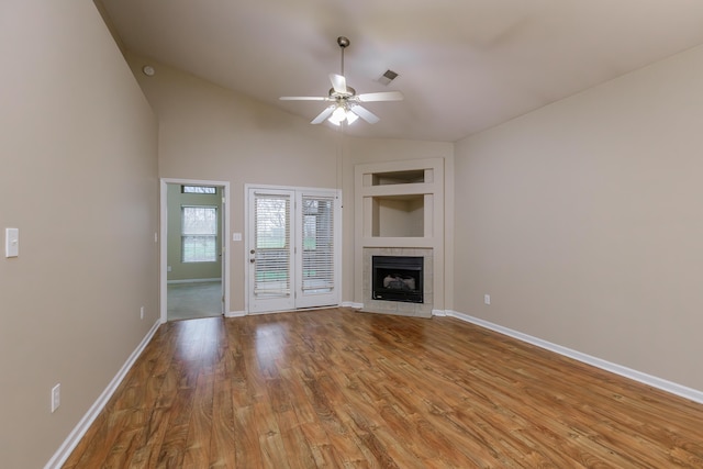 unfurnished living room with ceiling fan, a fireplace, vaulted ceiling, and light wood-type flooring