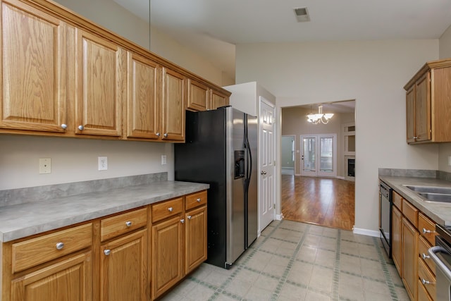 kitchen with sink, a notable chandelier, stainless steel fridge with ice dispenser, black dishwasher, and hanging light fixtures