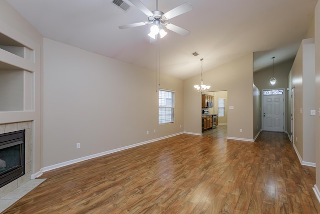 unfurnished living room featuring hardwood / wood-style floors, ceiling fan with notable chandelier, lofted ceiling, and a fireplace