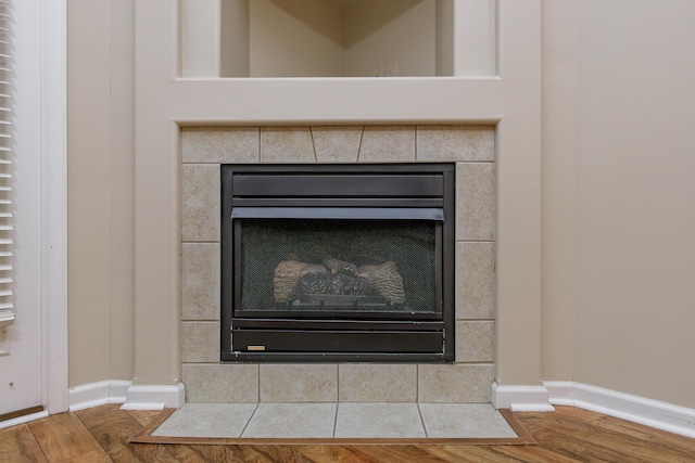 interior details with a tile fireplace and hardwood / wood-style flooring