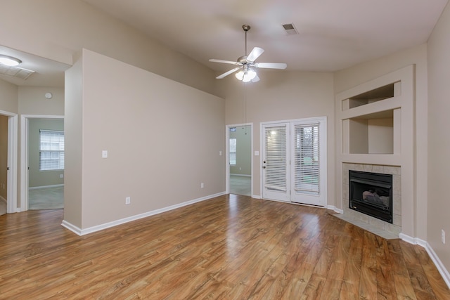 unfurnished living room featuring a tile fireplace, light hardwood / wood-style flooring, ceiling fan, and lofted ceiling