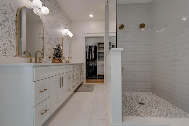 bathroom with tile patterned flooring, vanity, and a tile shower