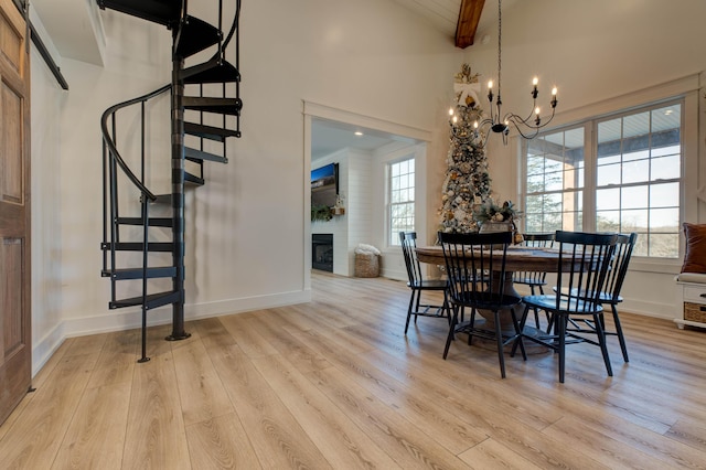 dining area featuring beam ceiling, a large fireplace, an inviting chandelier, light hardwood / wood-style flooring, and high vaulted ceiling