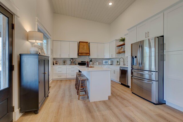 kitchen with stainless steel appliances, a kitchen island, light hardwood / wood-style flooring, a breakfast bar area, and white cabinets