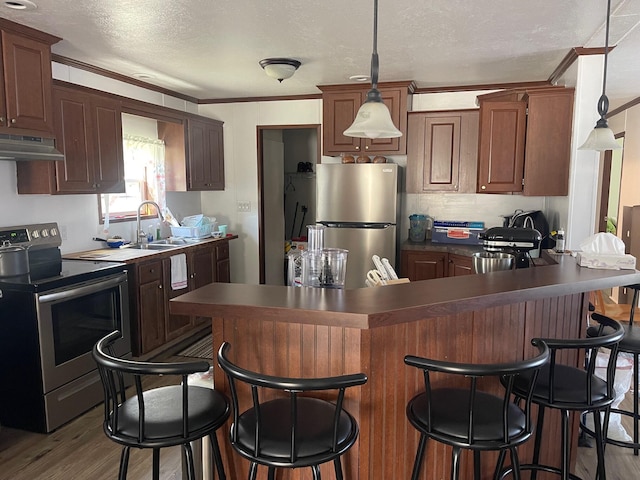 kitchen featuring sink, ornamental molding, a textured ceiling, appliances with stainless steel finishes, and light hardwood / wood-style floors