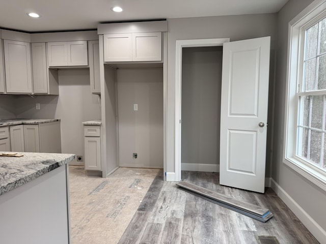 kitchen featuring gray cabinets, light stone counters, and light wood-type flooring