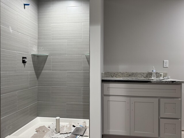 bathroom with a tile shower and vanity