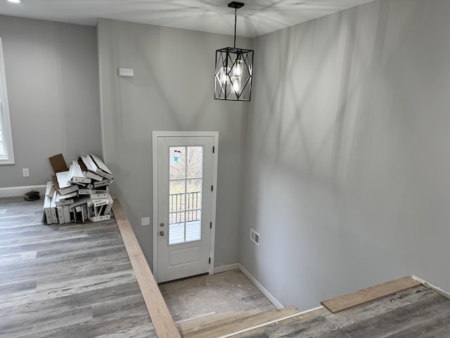 doorway to outside with a notable chandelier