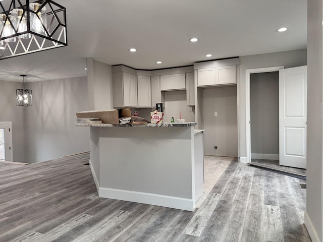 kitchen with pendant lighting, a notable chandelier, dark stone counters, and light hardwood / wood-style flooring