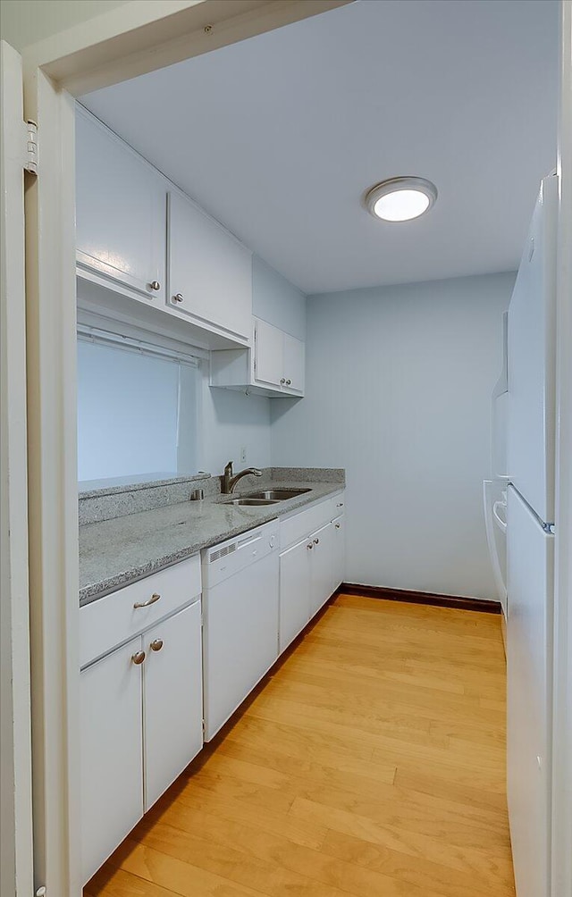 kitchen featuring light stone countertops, white cabinetry, sink, light hardwood / wood-style floors, and white appliances