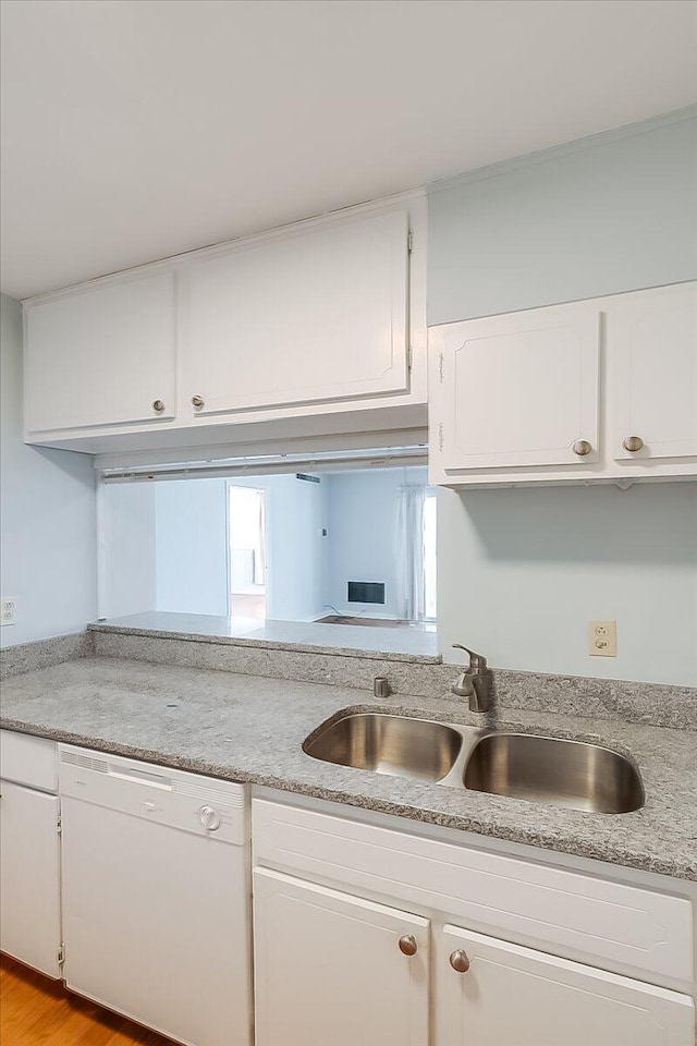 kitchen featuring white dishwasher, light wood-type flooring, white cabinetry, and sink