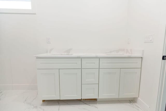bathroom with double vanity, marble finish floor, and baseboards