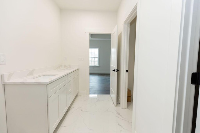 bathroom featuring baseboards, marble finish floor, a sink, and double vanity