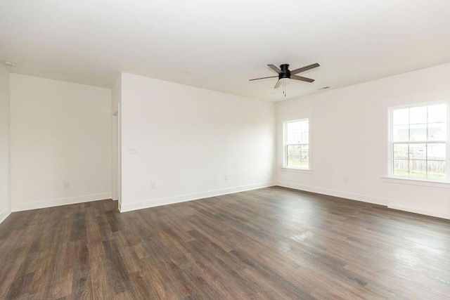 empty room featuring ceiling fan, baseboards, visible vents, and dark wood-style floors