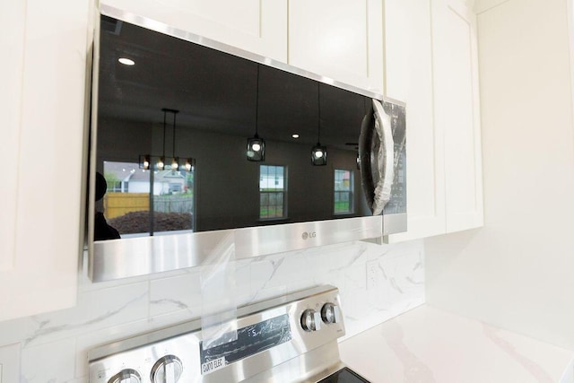interior details featuring white cabinetry, tasteful backsplash, stainless steel range, and light countertops