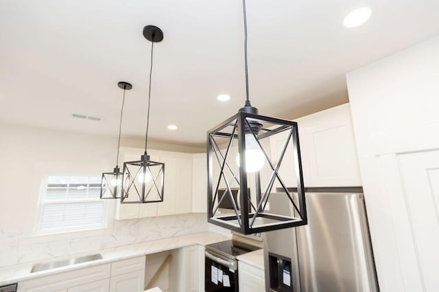room details featuring stainless steel appliances, backsplash, visible vents, a sink, and white cabinetry