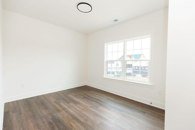 empty room featuring baseboards, visible vents, and dark wood-style floors