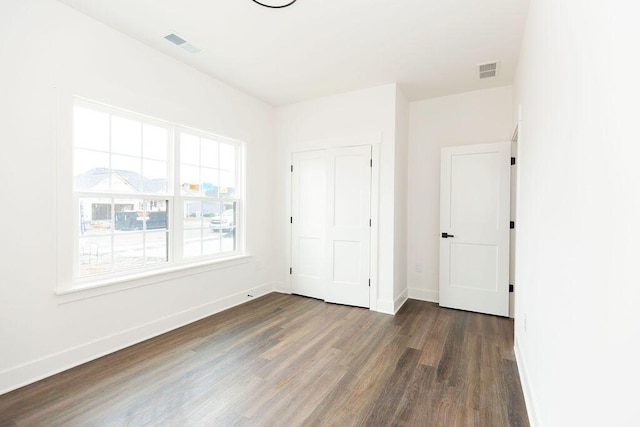 unfurnished bedroom with visible vents, baseboards, and wood finished floors