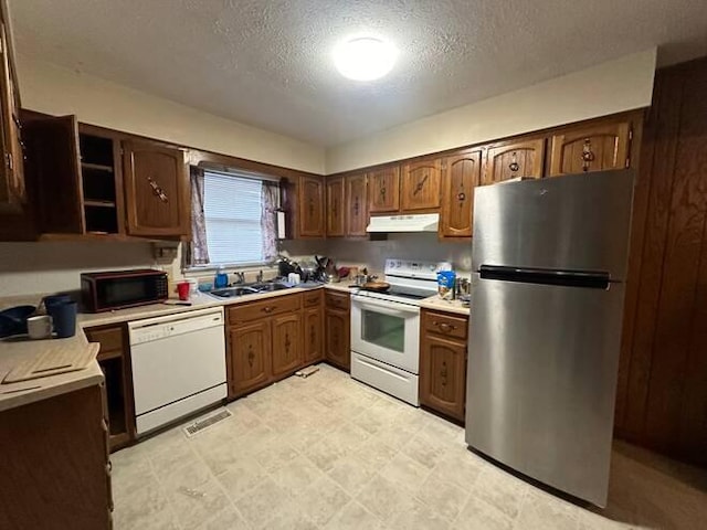 kitchen featuring a textured ceiling, white appliances, dark brown cabinetry, and sink