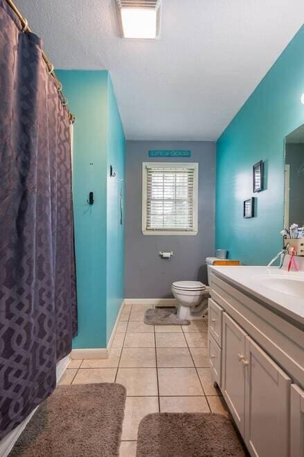 bathroom with tile patterned flooring, a textured ceiling, vanity, and toilet