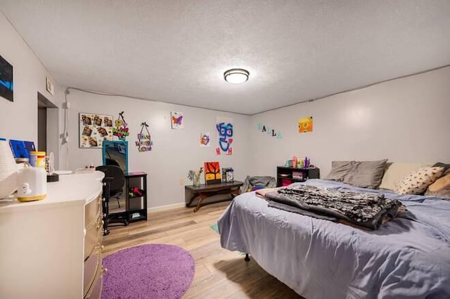 bedroom with a textured ceiling and light hardwood / wood-style flooring