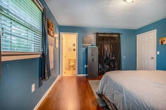 bedroom with a textured ceiling, dark wood-type flooring, connected bathroom, and a closet