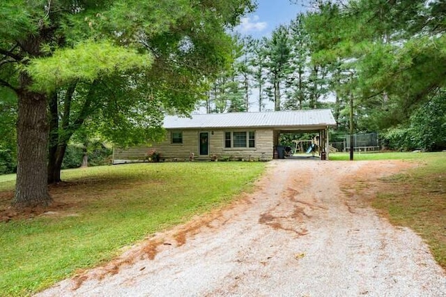 ranch-style house featuring a front yard, a trampoline, and a carport